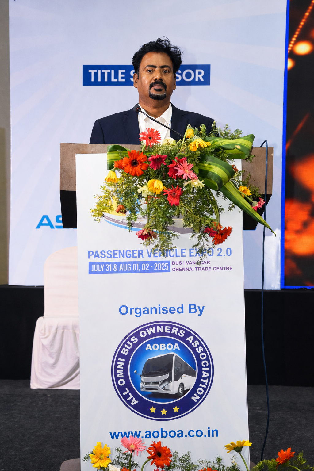 Dr. V. Amudhan speaking at the podium at Passenger Vehicle Expo 2.0, Chennai