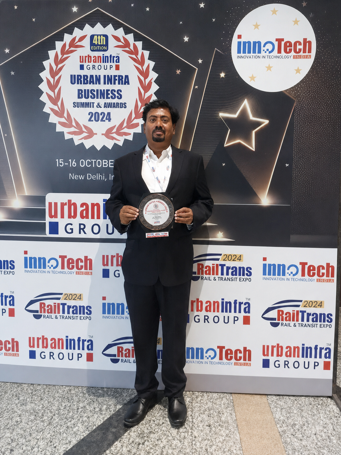 Dr. V. Amudhan holding an award plaque at Urban Infra Business Summit & Awards 2024