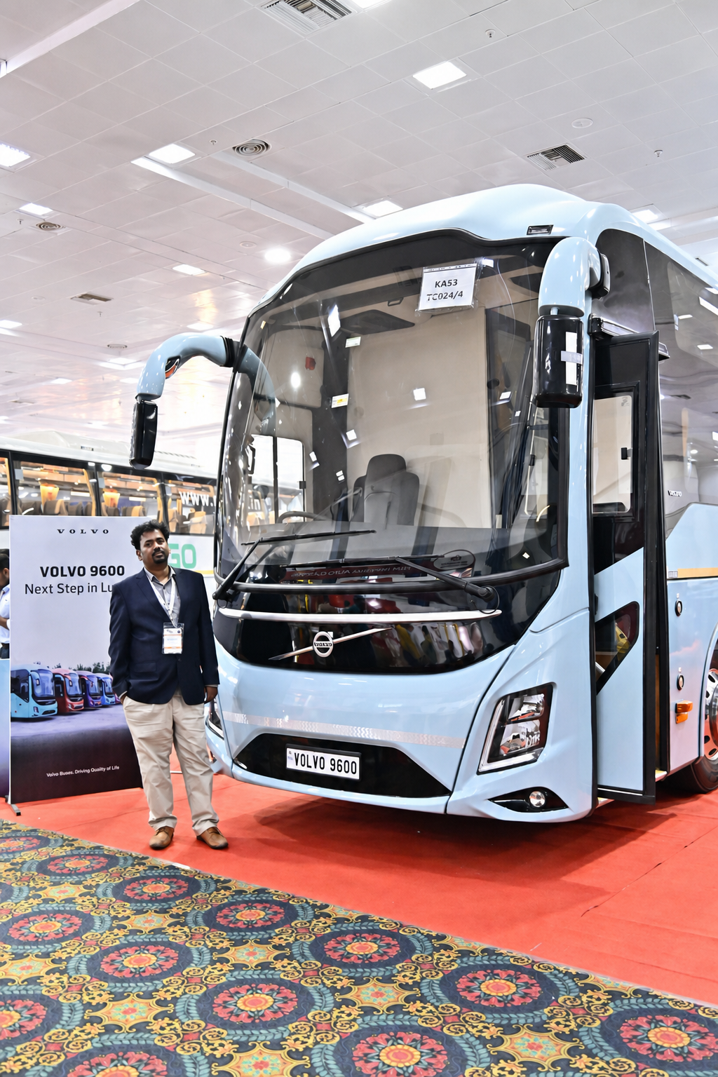 Dr. V. Amudhan standing beside a Volvo 9600 coach at an expo